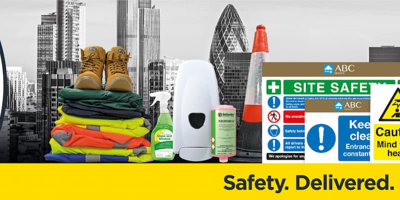 Work boots placed on top of workwear items with safety signage, cleaning products and traffic cone